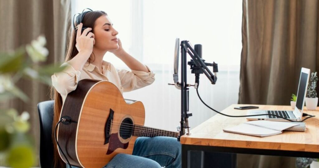 A woman sits at a desk with a guitar and microphone, reflecting on the meaning of "I Used to Know" lyrics.